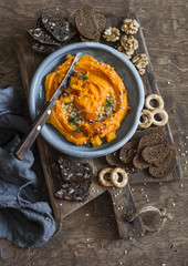 Healthy vegetarian snack - pumpkin hummus on a wooden cutting board, top view