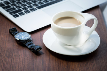 laptop with watch and cup of coffee on brown wooden table...
