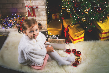 Cute toddler girl decorating a Christmas tree. Red balls.