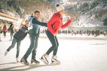 Happy family outdoor ice skating at rink. Winter activities