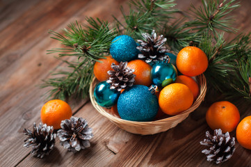 composition of Christmas toys, tangerines, pine branch cone basket wooden background