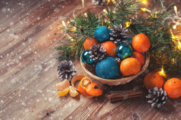 Fototapeta na wymiar composition of Christmas toys, tangerines, pine branch cone garland basket wooden background