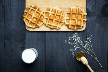 waffles with honey and milk on a black background.Homemade Waffles, Belgian waffles with honey and milk, food styling...