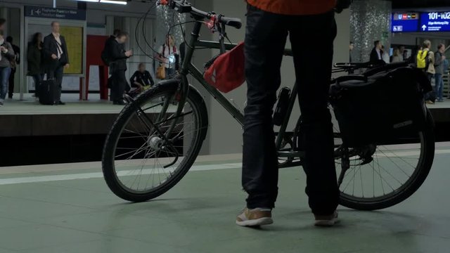 Man parking his bicycle on the platform of underground station and waiting for the next train