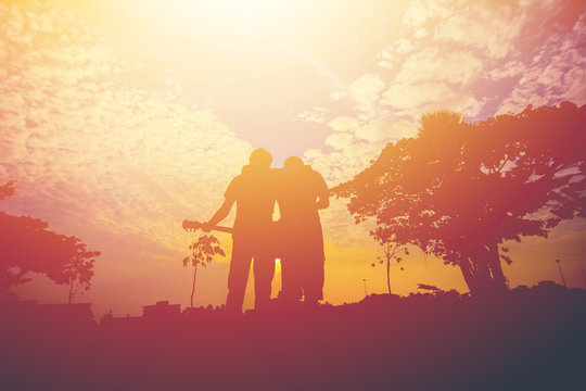 Silhouette of two men hug on sunset.
