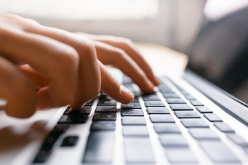 Hands using laptop type on keyboard, simple clean close up image with sun flare