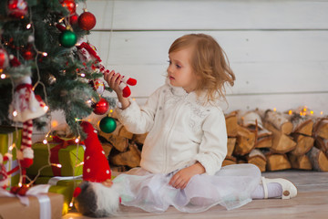 Little beautiful girl in a white dress decorated with  Christmas tree