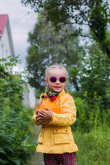 Portrait of cute young girl with two braids in sunglasses spring day in the garden with melon