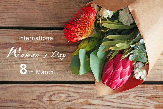 Beautiful flowers on wooden table. Text INTERNATIONAL WOMAN'S DAY, 8TH MARCH on background