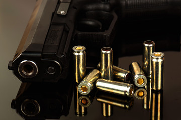 The black gun and cartridges to him on a black background close up.