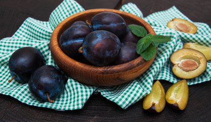 Bowl with  plums with green leaves