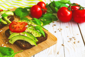 Toast with sliced avocado, tomatoes, spinach and spices