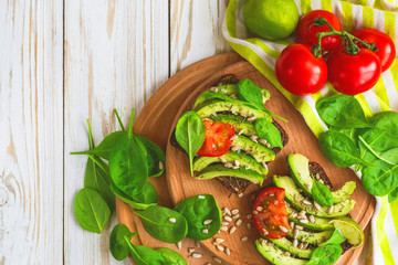 Toast with sliced avocado, tomatoes, spinach and spices