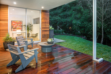 Fototapeta premium Wooden deck / balcony at night with furniture and open doors lea