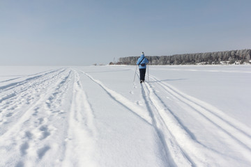 The woman in a blue jacket skiing on the snow of the river