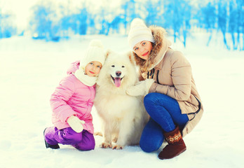 Mom and little child with white Samoyed dog winter