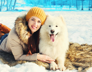 smiling woman owner and white Samoyed dog winter lying on snow