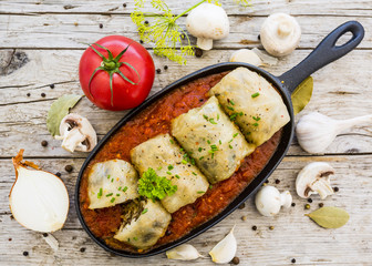 Fototapeta na wymiar Stuffed cabbage with rice and mushroom with meat in tomato sauce on wooden rustic background.