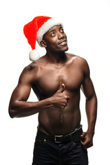 Muscular black shirtless young man in Santa Claus hat - obrazy, fototapety, plakaty