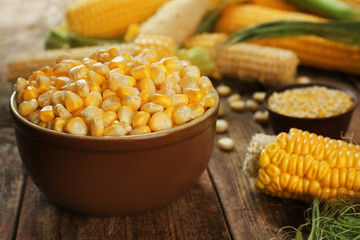 Corn seeds in bowl on wooden table, closeup