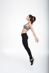 Portrait of young brunette sports woman jumping and looking away