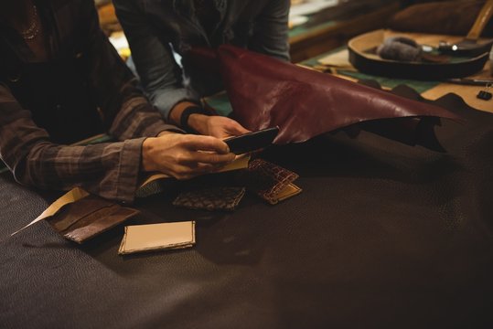 Craftswomen discussing over a sheet of leather
