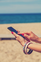 Girl holding a cellphone with sea/ocean background.
