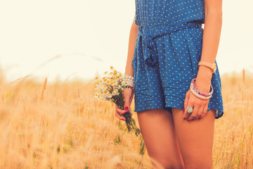 Girl holding flower bouquet in wheat field.