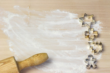 Cookie cutter mold and wooden rolling pin on a floured wooden board. Free place for your text is in...