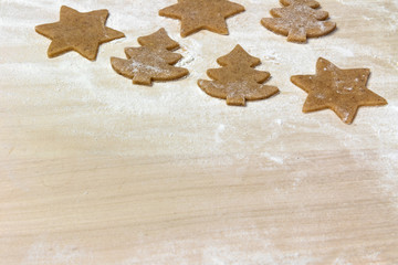 Cutted out shapes of cookies on the floured wooden board