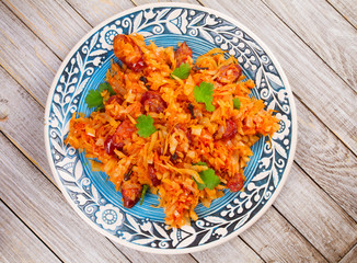 Stewed cabbage with sausages, carrot, onion and tomatoes. View from above, top studio shot