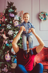 The father and son sitting near Christmas Tree