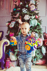 The small boy keeps toys near Christmas Tree