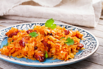 Stewed cabbage with sausages, carrot, onion and tomatoes