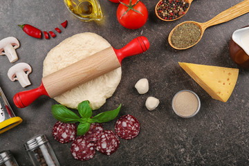 Raw dough for pizza with ingredients and spices on table