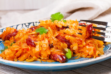 Stewed cabbage with sausages, carrot, onion and tomatoes