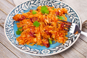 Stewed cabbage with sausages, carrot, onion and tomatoes