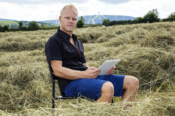 Man with tablet PC in haymaking