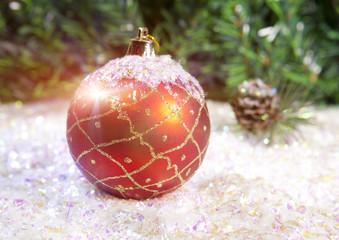 New Year's ball on a background of decorative snow and branch of a fir tree