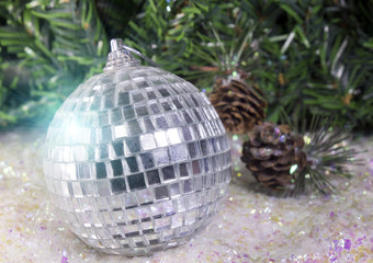 New Year's ball on a background of decorative snow and branch of a fir tree