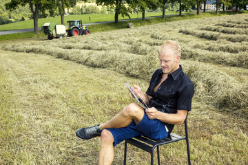 Fototapeta premium Man with tablet PC in haymaking