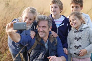 Fototapeta premium Man with kids in field taking selfie picture