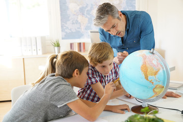 Teacher with kids in geography class looking at globe
