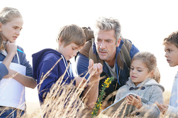 Teacher taking kids to countryside to explore plants and flowers