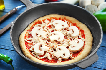Unbaked pizza in pan on wooden table