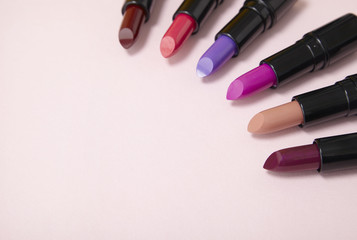 Lipstick make up arranged on a pastel pink background forming a page header with blank space at side