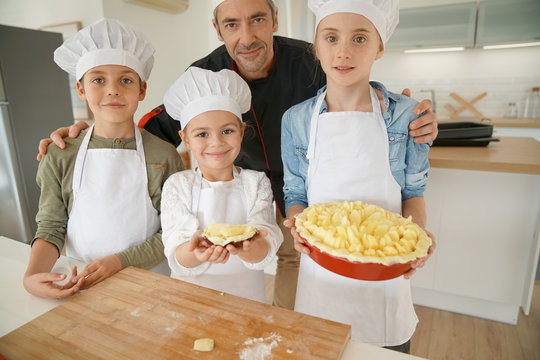Portrait of pastry chef with pupils holding apple pie