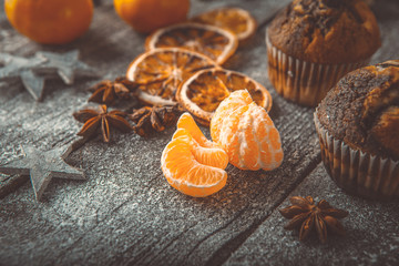 Xmas or new year composition with holiday decoration - Homemade cupcakes, sliced dried oranges and mandarin on wooden background with spruce twigs and christmas toy. Christmas card. Space for text © kulniz