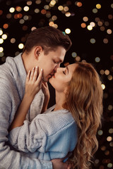 Cheerful couple in winter clothes hugging and kissing. Low light