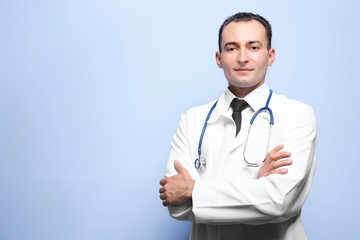 Practitioner with crossed hands standing on light background